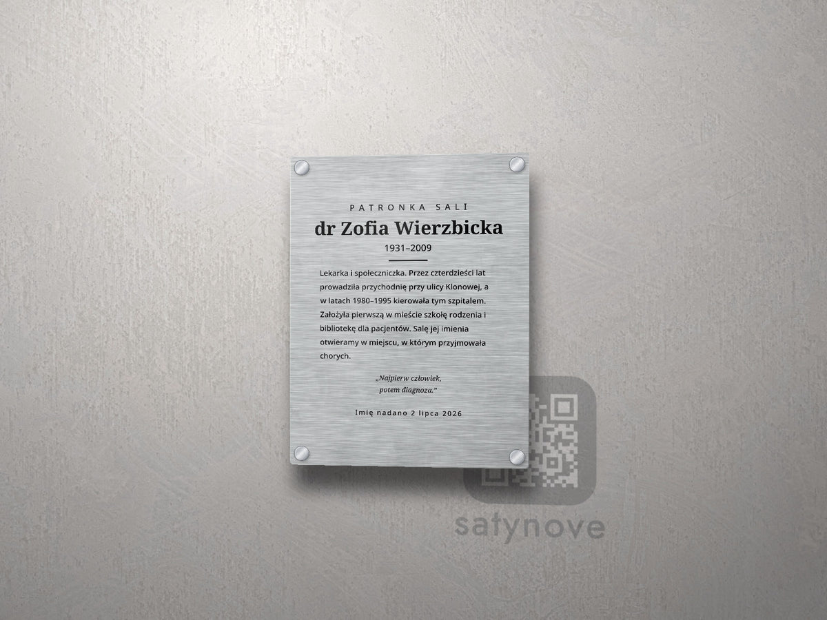 Pionowa tablica patrona sali: imię, lata życia, biogram, cytat kursywą i data nadania imienia