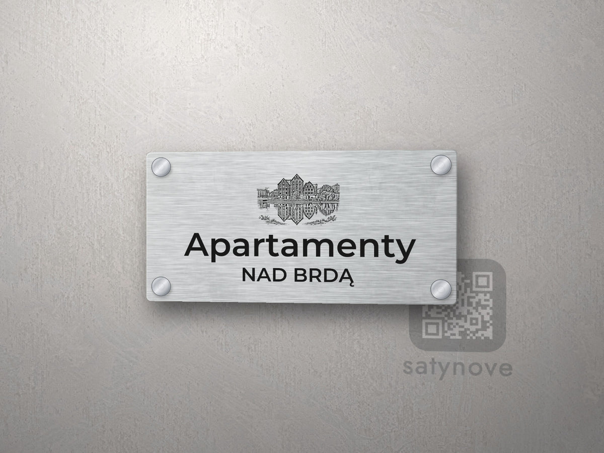 Srebrny szyld z grafiką Bydgoszczy i napisem Apartamenty nad brdą