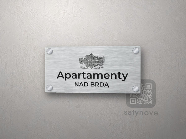 Srebrny szyld z grafiką Bydgoszczy i napisem Apartamenty nad brdą
