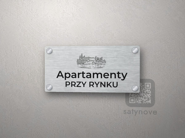 Srebrny szyld z grafiką Krakowa i napisem Apartamenty przy rynku