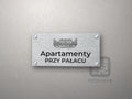 Srebrny szyld z grafiką Białegostoku i napisem Apartamenty przy pałacu
