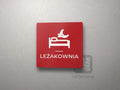 Czerwona kwadratowa tabliczka z obrazkiem i napisem LEŻAKOWNIA