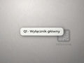Biała tabliczka z napisem Q1 · Wyłącznik główny