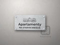 Srebrny szyld z grafiką Lublina i napisem Apartamenty na starym mieście