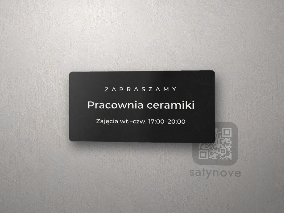 Czarna tabliczka: etykieta „ZAPRASZAMY”, napis „Pracownia ceramiki” i linia