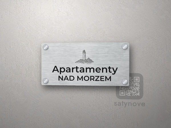 Srebrny szyld z grafiką morską i napisem Apartamenty nad morzem