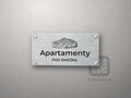Srebrny szyld z grafiką Karkonoszy i napisem Apartamenty pod śnieżką