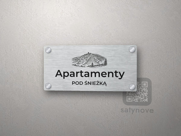Srebrny szyld z grafiką Karkonoszy i napisem Apartamenty pod śnieżką