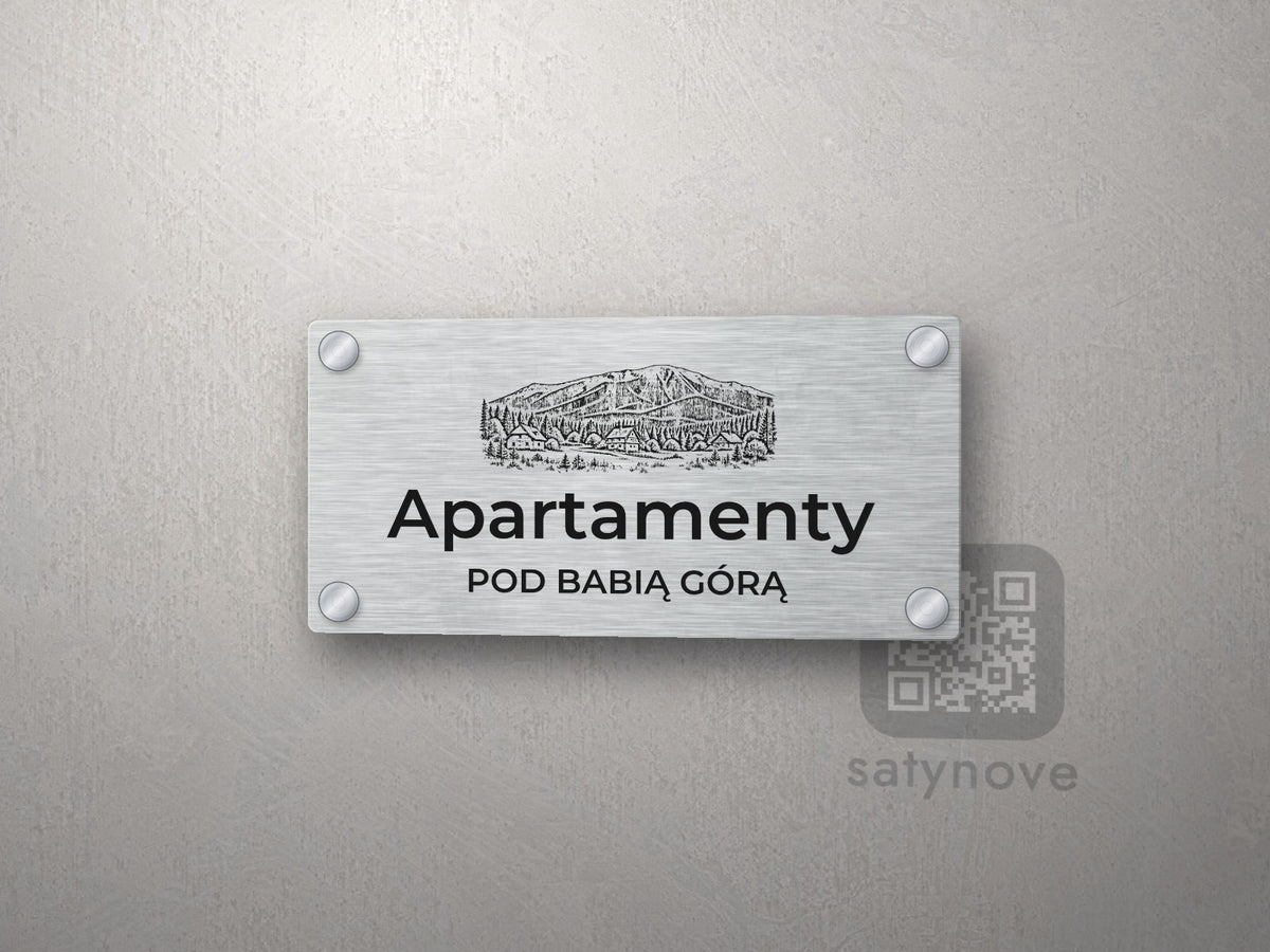 Srebrny szyld z grafiką Beskidów i napisem Apartamenty pod babią górą