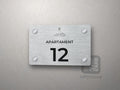 Srebrna tabliczka z numerem apartamentu 12 i grafiką morską