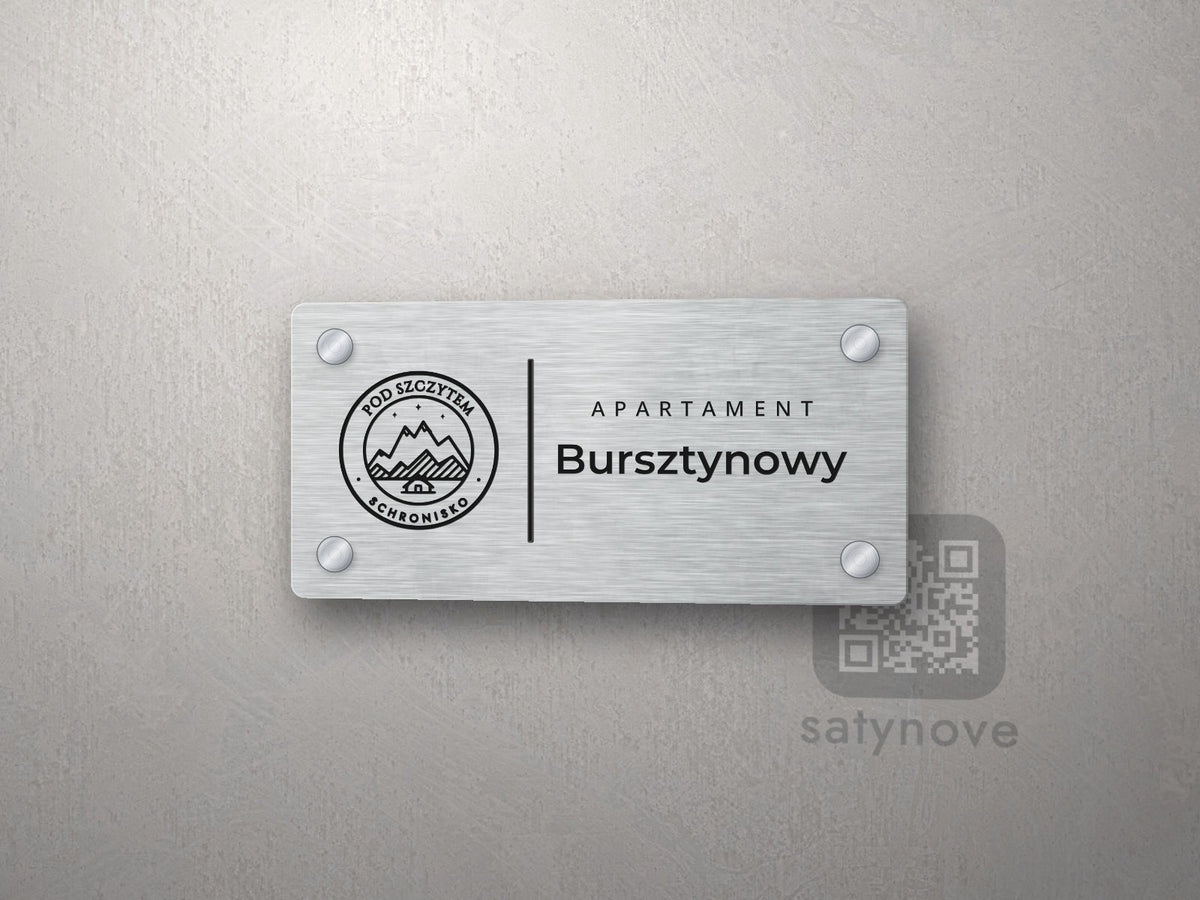 Srebrna tabliczka apartamentu z logo schroniska, linią, napisem APARTAMENT i nazwą Bursztynowy