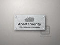 Srebrny szyld z grafiką Pienin i napisem Apartamenty pod trzema koronami