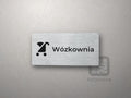 Srebrna tabliczka z piktogramem i napisem Wózkownia