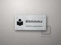 Tabliczka na drzwi z piktogramem książki i napisem Biblioteka