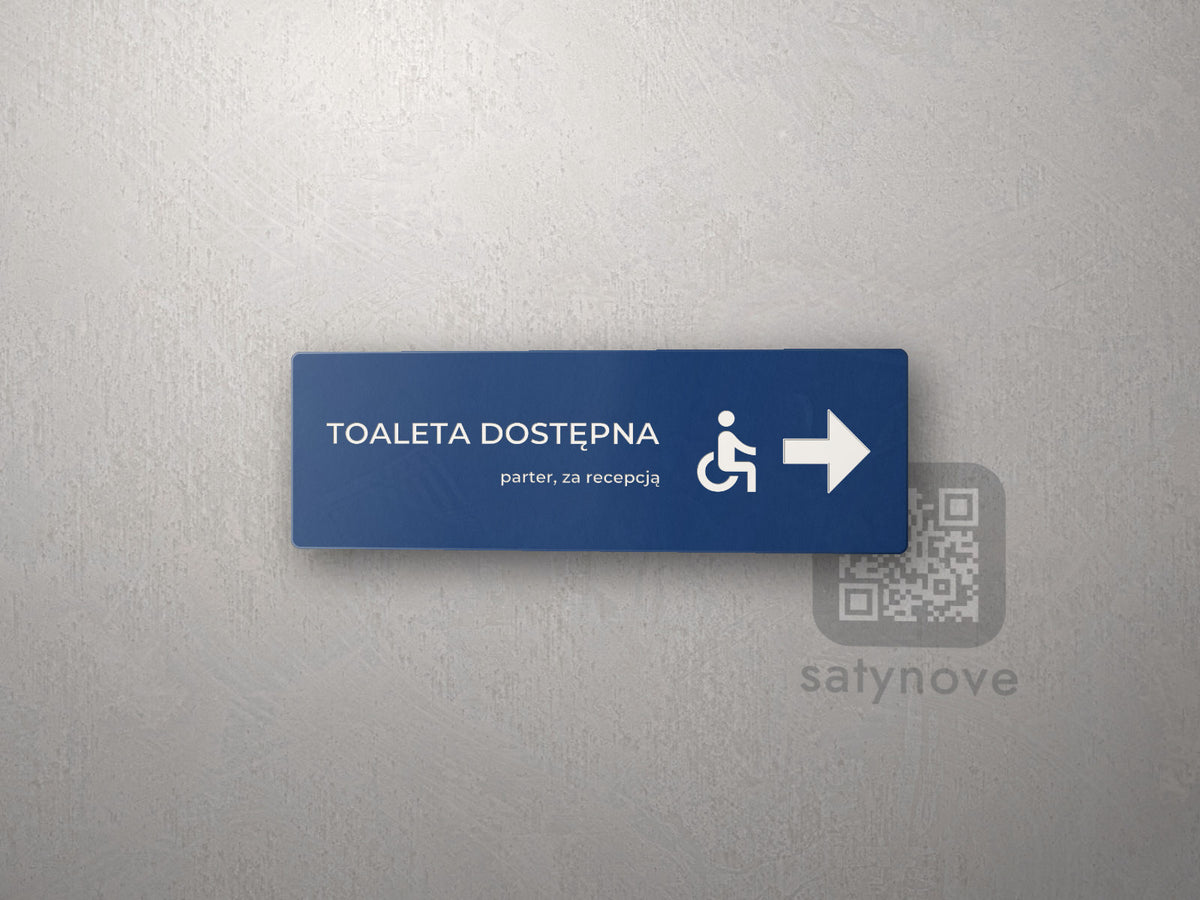 Granatowa tabliczka kierunkowa Toaleta dostępna z symbolem wózka i strzałką