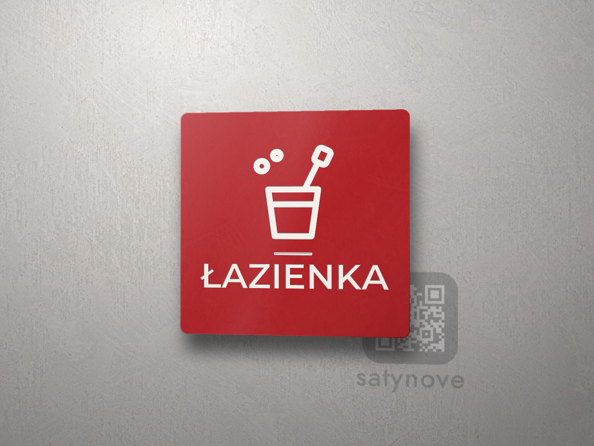 Czerwona kwadratowa tabliczka z obrazkiem i napisem ŁAZIENKA