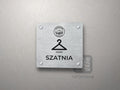 Srebrna tabliczka Szatnia z logo schroniska u góry, piktogramem i podpisem SZATNIA