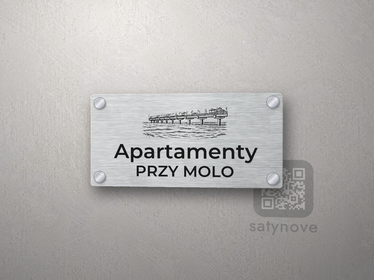 Srebrny szyld z grafiką Międzyzdrojów i Świnoujścia i napisem Apartamenty przy molo