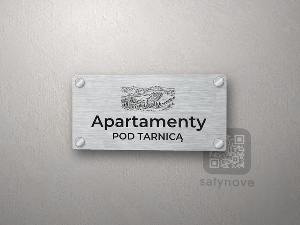 Srebrny szyld z grafiką Bieszczadów i napisem Apartamenty pod tarnicą