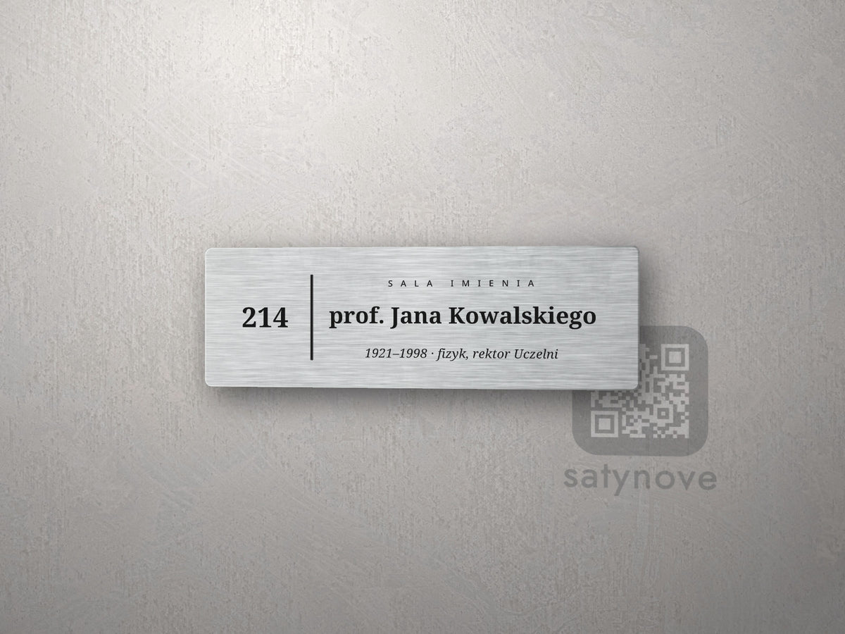 Tabliczka z numerem 214, napisem „Sala imienia” i imieniem patrona z prawej