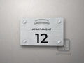 Srebrna tabliczka z numerem apartamentu 12 i grafiką Katowic