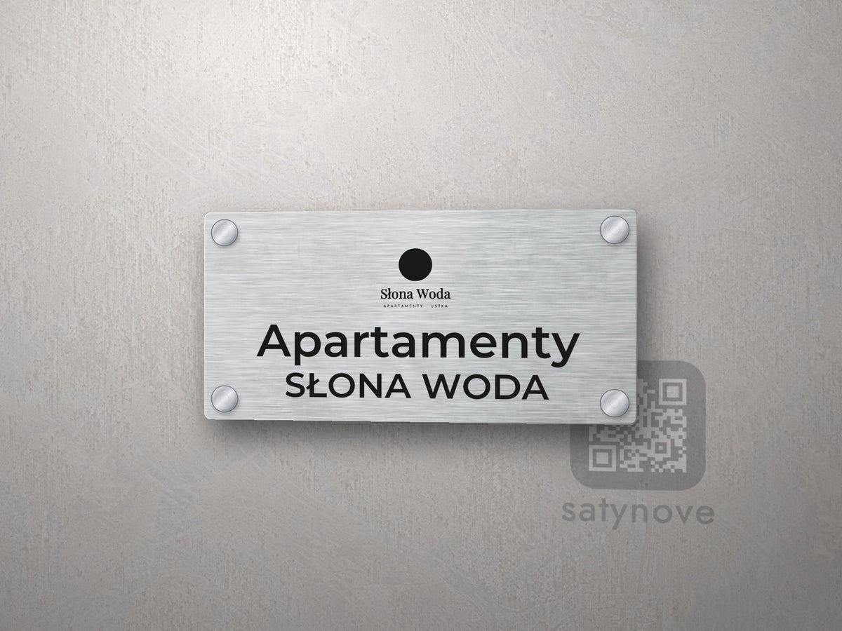 Srebrny szyld z logo obiektu i napisem Apartamenty Słona Woda