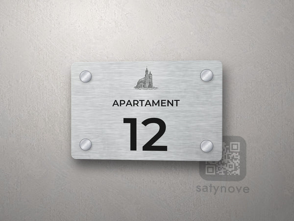 Srebrna tabliczka z numerem apartamentu 12 i grafiką Krakowa