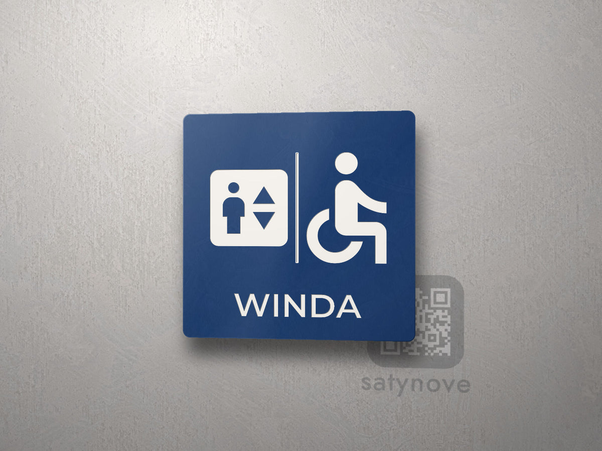 Tabliczka z symbolem windy i osoby na wózku oraz napisem Winda
