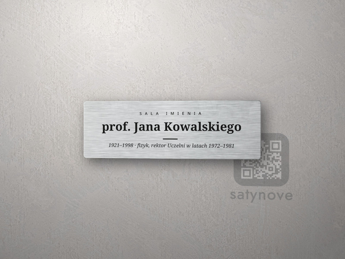 Srebrna tabliczka „Sala imienia prof. Jana Kowalskiego” z notą o patronie kursywą