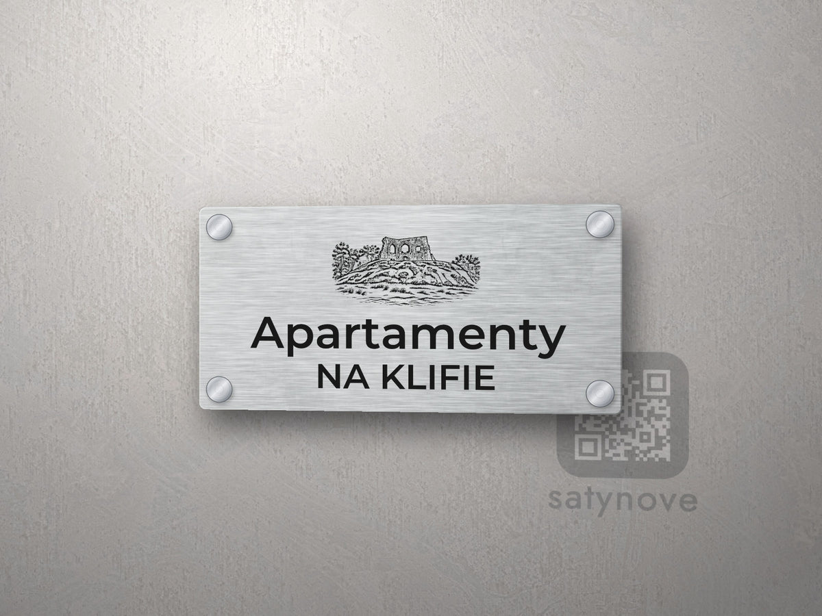 Srebrny szyld z grafiką Wybrzeża Rewalskiego i napisem Apartamenty na klifie