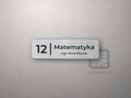 Mała srebrna tabliczka z numerem 12 i napisem Matematyka