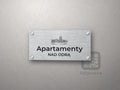 Srebrny szyld z grafiką Wrocławia i napisem Apartamenty nad odrą
