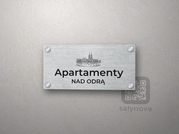 Srebrny szyld z grafiką Wrocławia i napisem Apartamenty nad odrą