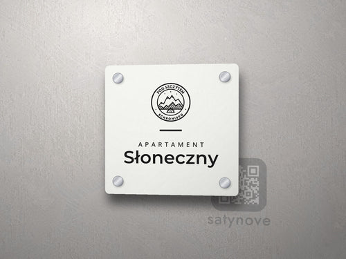 Biała kwadratowa tabliczka apartamentu z logo schroniska, linią i nazwą Słoneczny