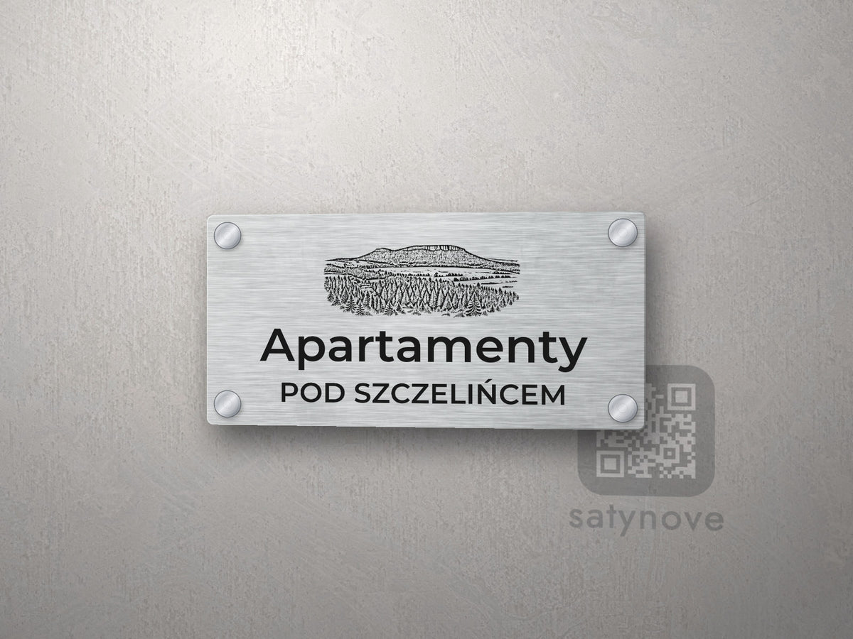 Srebrny szyld z grafiką Gór Stołowych i napisem Apartamenty pod szczelińcem