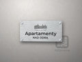 Srebrny szyld z grafiką Szczecina i napisem Apartamenty nad odrą