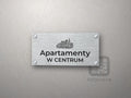 Srebrny szyld z grafiką Katowic i napisem Apartamenty w centrum